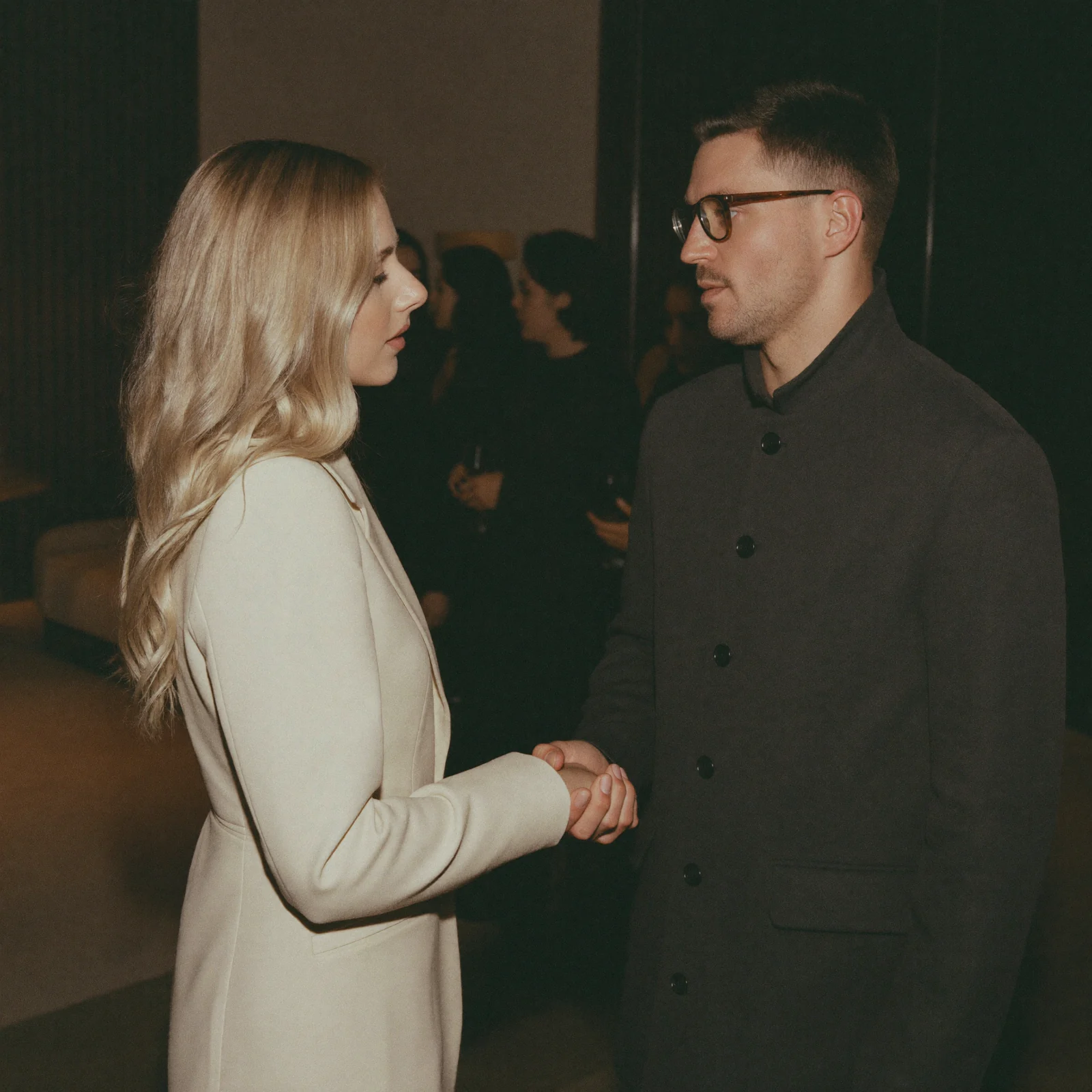 Two professionals shaking hands at an evening networking event